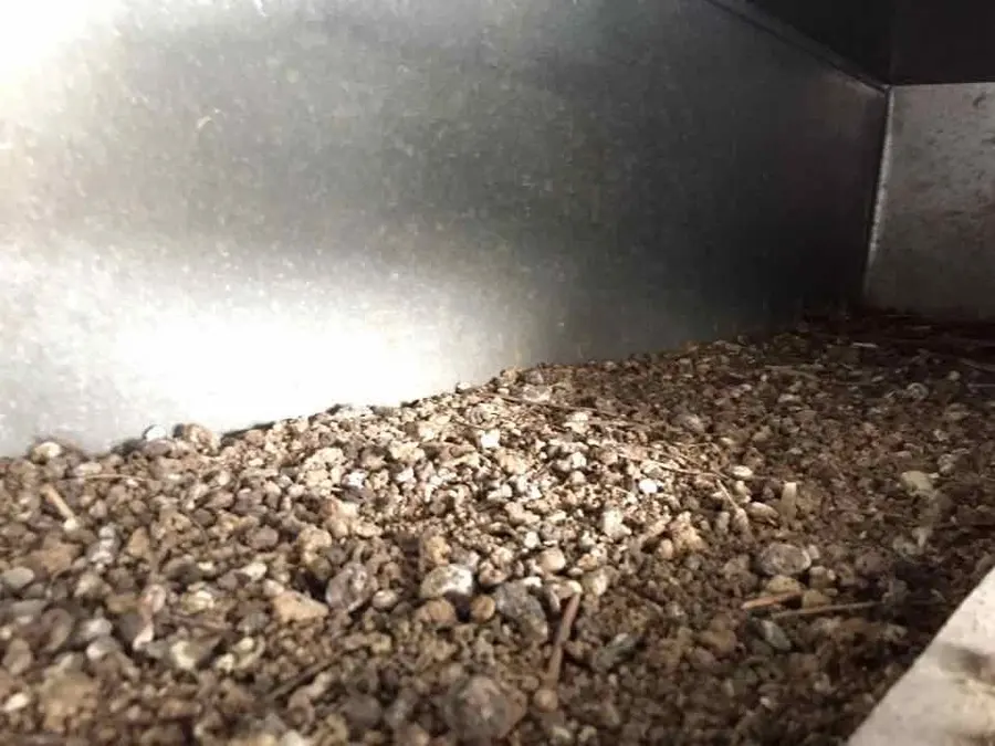 The floor of a duct run under a thick layer of coarse grey debris