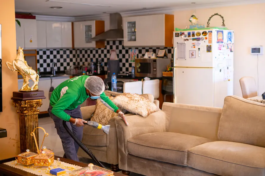 An iPurity technician extraction-cleaning a cream sofa in a family living room