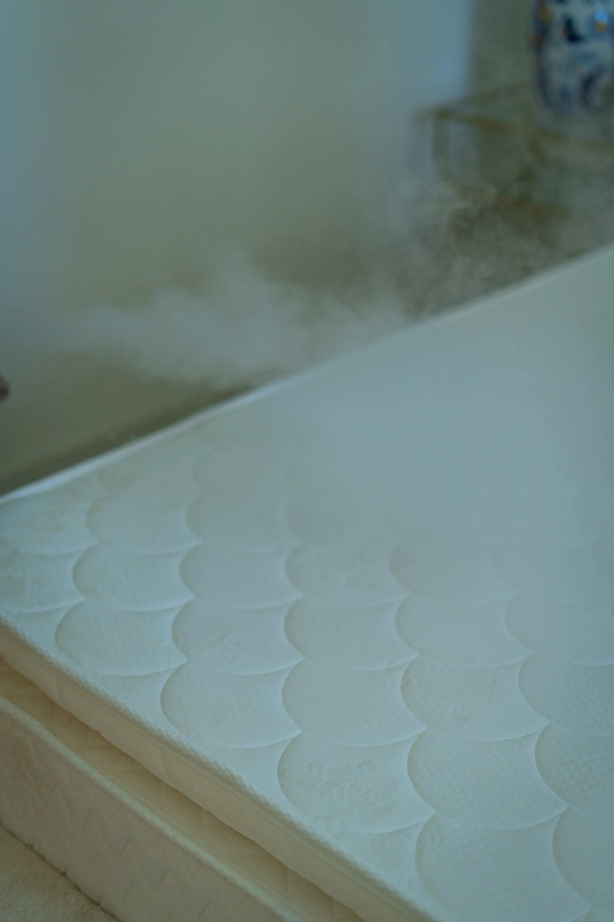 Steam rising from the quilted surface of a mattress during treatment