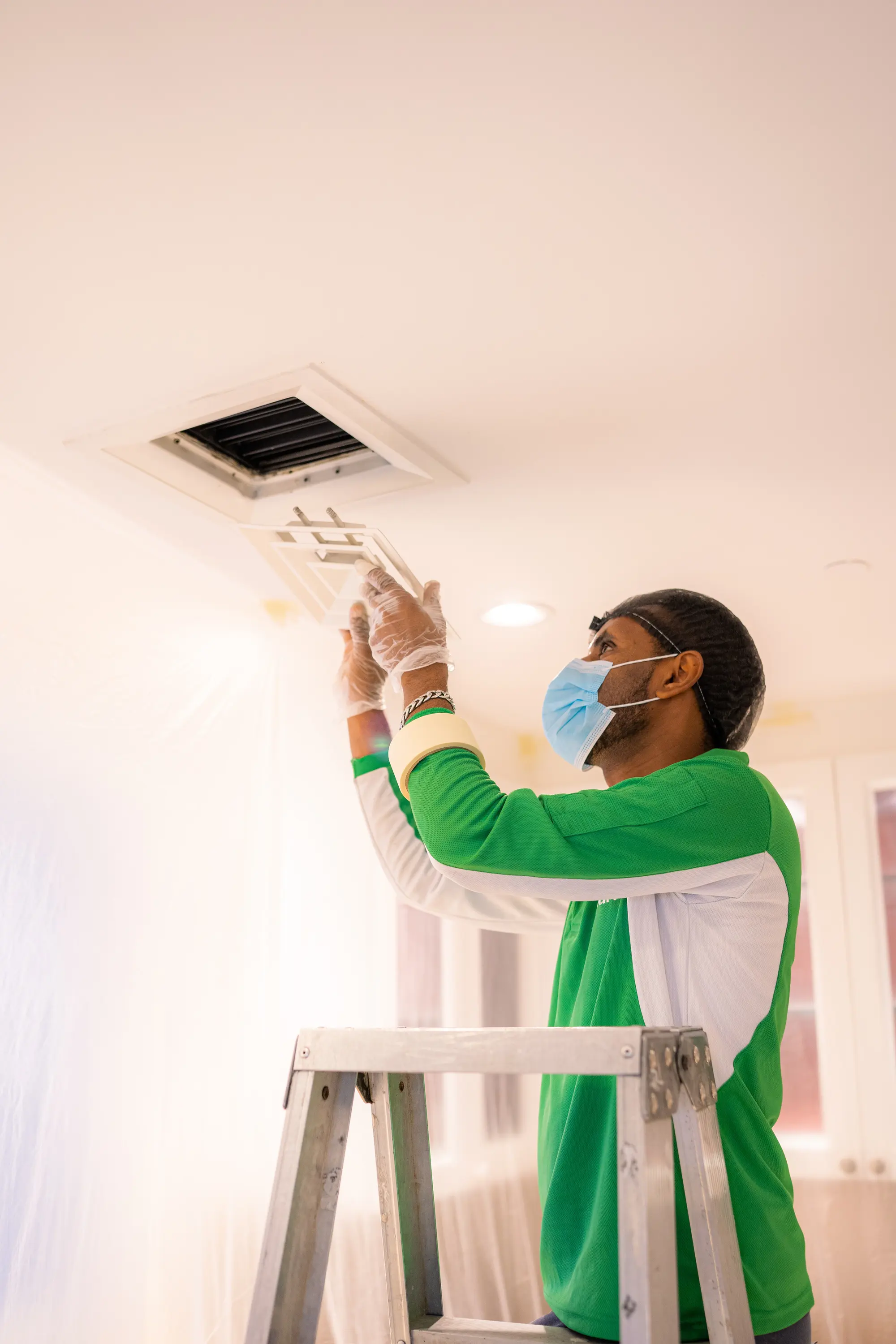 Technician removing a ceiling diffuser