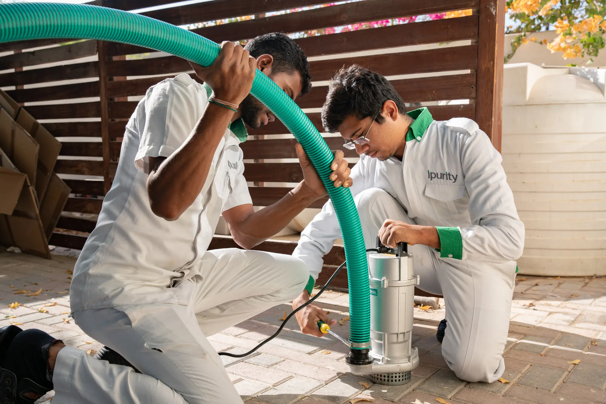 Two iPurity technicians setting up a pump to drain a water tank