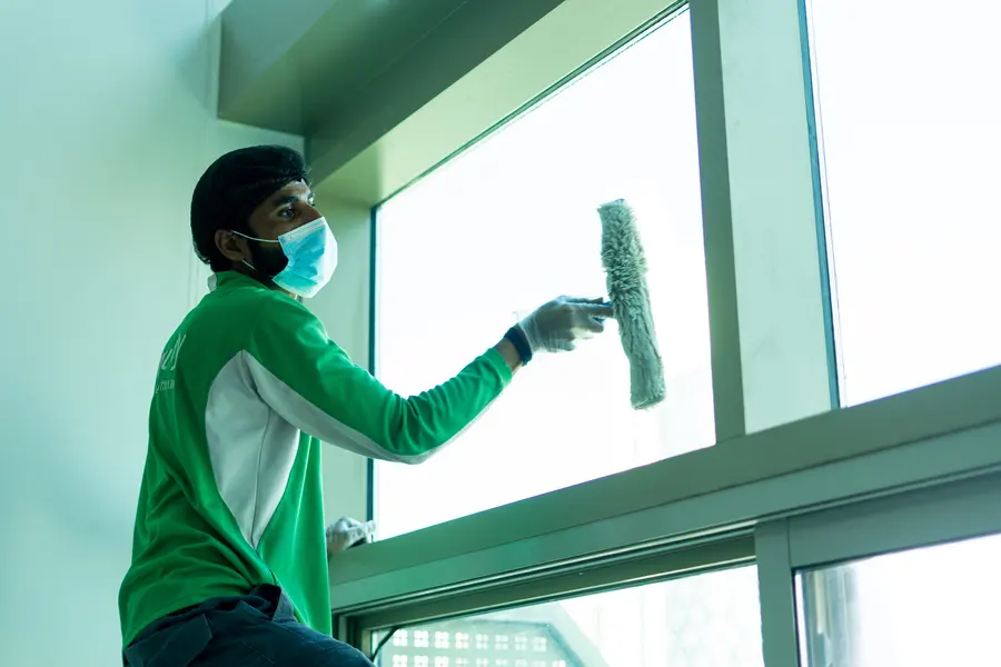 An iPurity technician cleaning a tall window with a strip washer